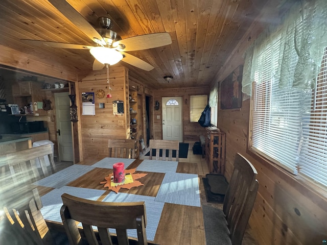 tiled dining space with ceiling fan, wooden ceiling, and wooden walls