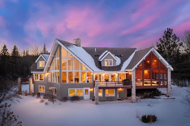 snow covered property featuring a sunroom and a chimney