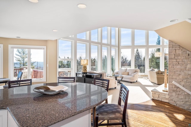 interior space with white cabinets, open floor plan, dark stone countertops, wood finished floors, and recessed lighting