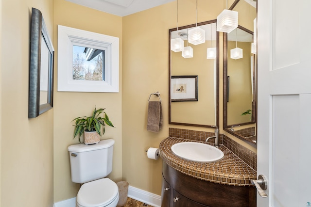 half bathroom featuring decorative backsplash, baseboards, vanity, and toilet