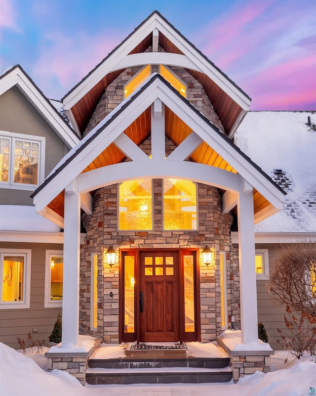 exterior entry at dusk with stone siding and a porch