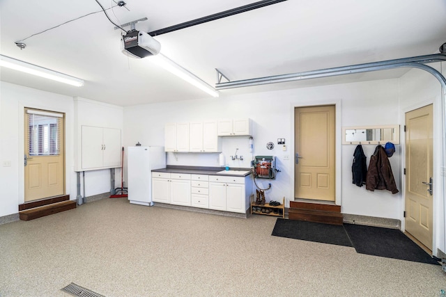 garage featuring a garage door opener, freestanding refrigerator, and baseboards