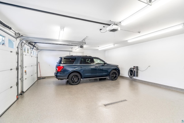 garage with a garage door opener, visible vents, and baseboards