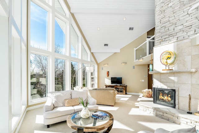 living area featuring baseboards, visible vents, carpet floors, a fireplace, and high vaulted ceiling