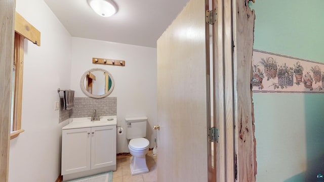 half bath with decorative backsplash, toilet, vanity, and tile patterned flooring