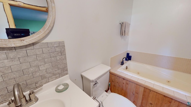 full bathroom with a jetted tub, toilet, and a sink