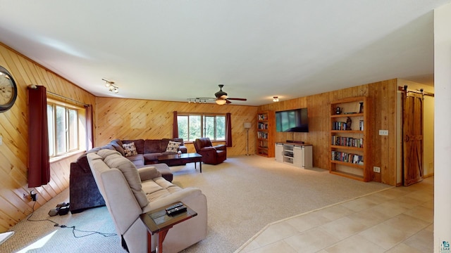 living room with a wealth of natural light, a barn door, light colored carpet, and ceiling fan