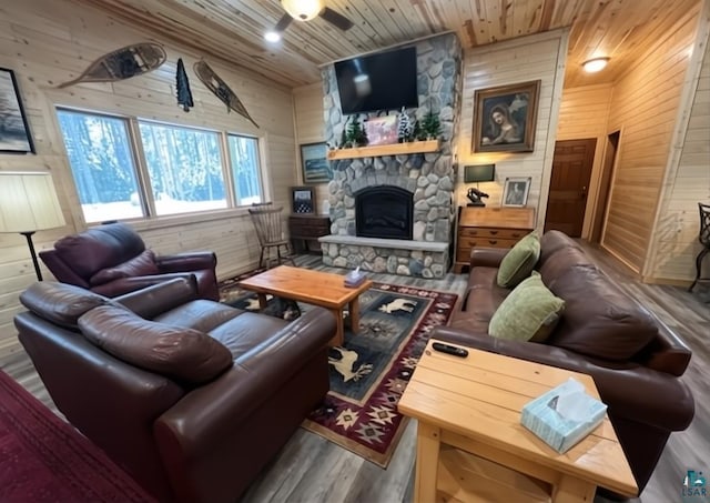 living area featuring a fireplace, ceiling fan, wooden walls, wood finished floors, and wooden ceiling