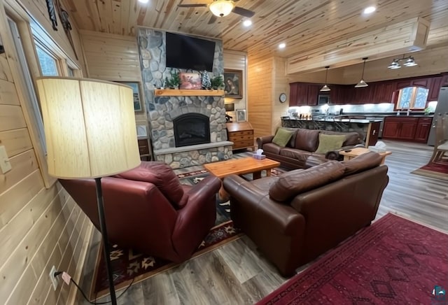 living area featuring wood ceiling, a fireplace, wood walls, and wood finished floors