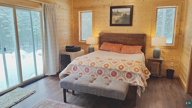 bedroom featuring multiple windows, wood walls, and wood finished floors