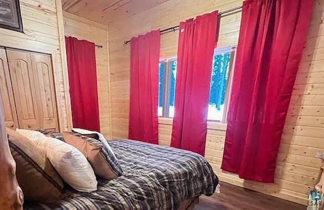 bedroom with wood finished floors and wooden walls