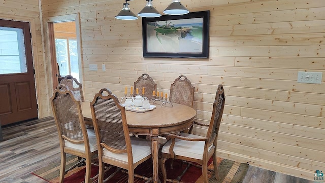 dining space featuring light wood-type flooring and wooden walls