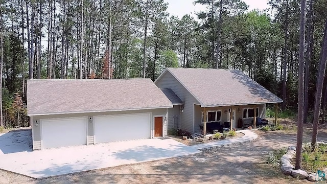 single story home with a shingled roof, covered porch, driveway, and an attached garage