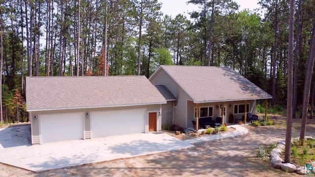 view of front facade featuring a porch, roof with shingles, driveway, and an attached garage