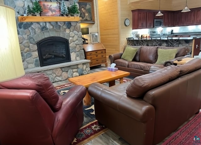 living room featuring a fireplace, wood walls, and wood finished floors