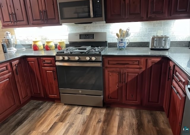 kitchen featuring dark wood-type flooring, tasteful backsplash, stainless steel appliances, and dark brown cabinets