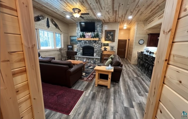 living area featuring wood ceiling, wooden walls, a fireplace, and wood finished floors