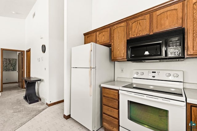 kitchen with white appliances, baseboards, light colored carpet, brown cabinets, and light countertops