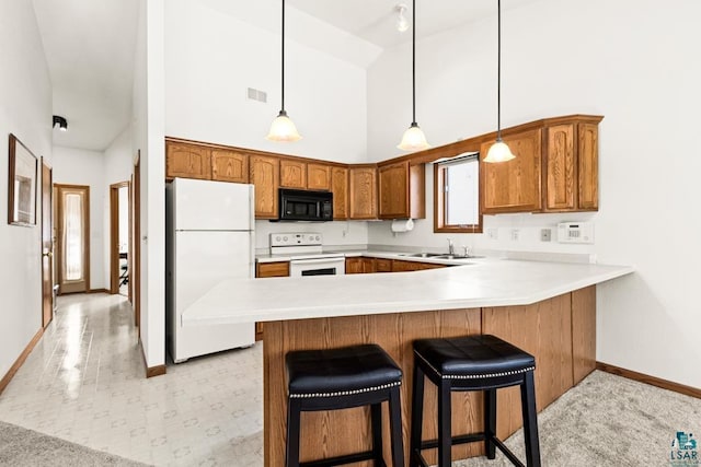 kitchen featuring white appliances, visible vents, brown cabinetry, a peninsula, and a sink