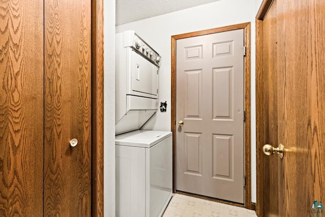 clothes washing area with a textured ceiling, laundry area, light floors, and stacked washer / drying machine