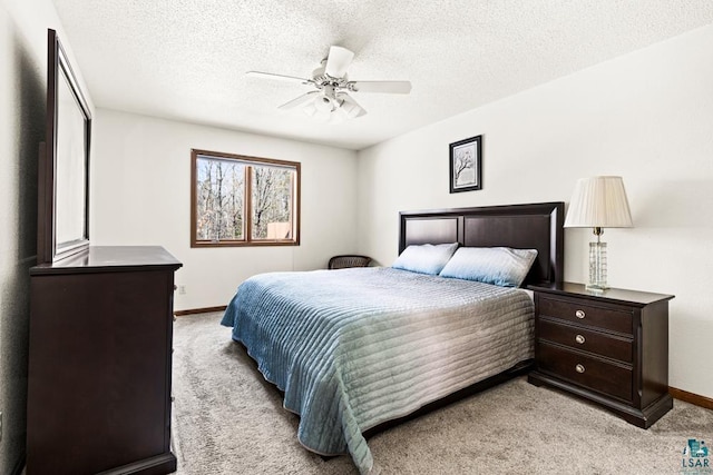 bedroom with ceiling fan, baseboards, a textured ceiling, and light colored carpet