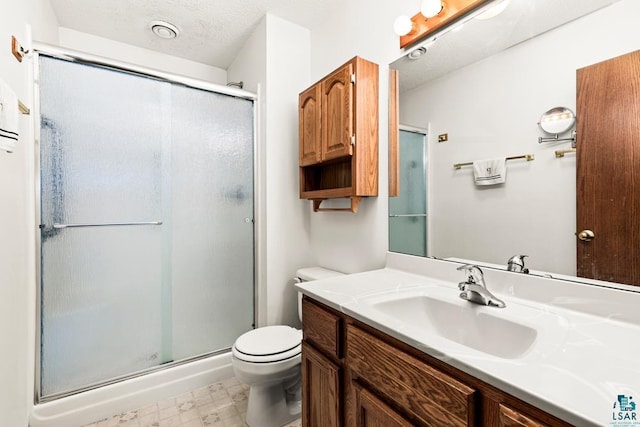 bathroom with toilet, a stall shower, vanity, a textured ceiling, and tile patterned floors