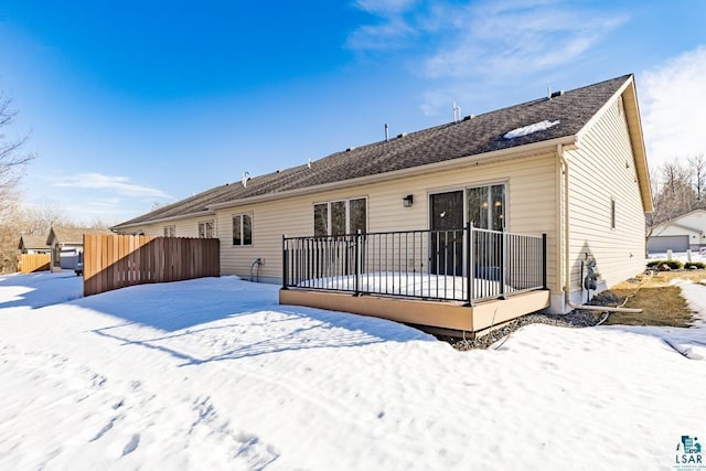 snow covered property with a deck and fence