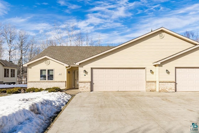 ranch-style home featuring an attached garage, roof with shingles, concrete driveway, and brick siding