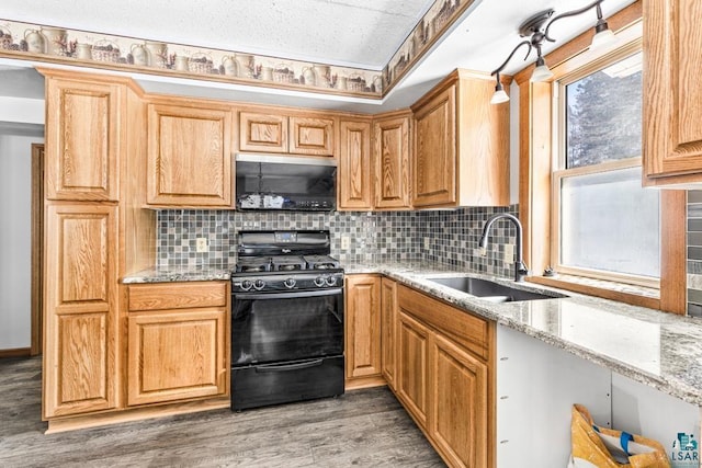 kitchen featuring light stone counters, light wood-style flooring, a sink, tasteful backsplash, and gas stove