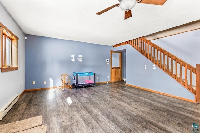 unfurnished room with stairway, baseboard heating, ceiling fan, wood finished floors, and baseboards