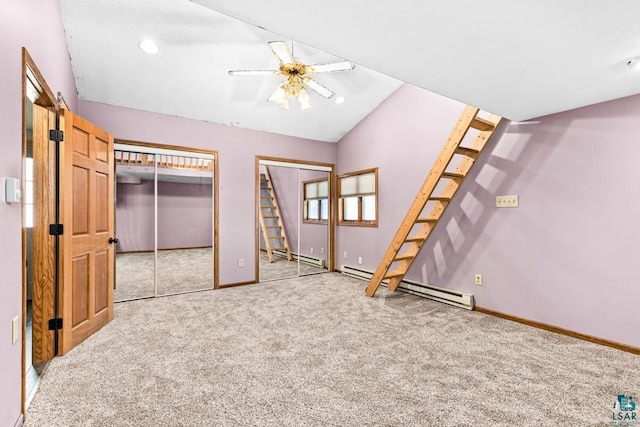 unfurnished bedroom featuring carpet, two closets, baseboard heating, vaulted ceiling, and baseboards