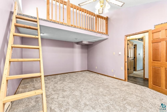 unfurnished bedroom with carpet floors, a high ceiling, and baseboards