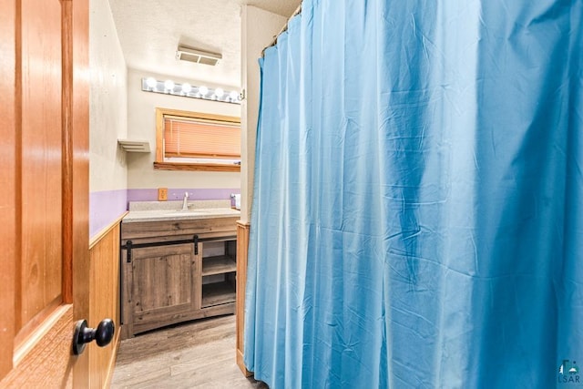 bathroom with curtained shower, a textured ceiling, wood finished floors, and vanity