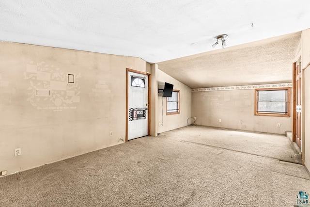 empty room featuring carpet floors, lofted ceiling, and a textured ceiling