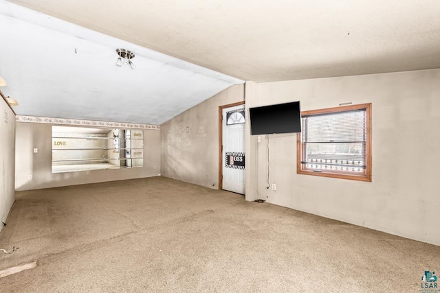 unfurnished living room featuring lofted ceiling and carpet flooring