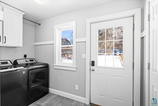 laundry area featuring light wood-type flooring, a wainscoted wall, cabinet space, and washing machine and clothes dryer