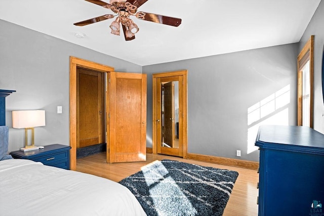 bedroom featuring a ceiling fan, baseboards, and wood finished floors