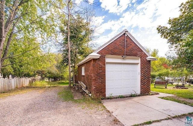 detached garage with concrete driveway and fence