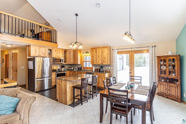 dining area featuring a chandelier, high vaulted ceiling, light tile patterned floors, baseboards, and french doors