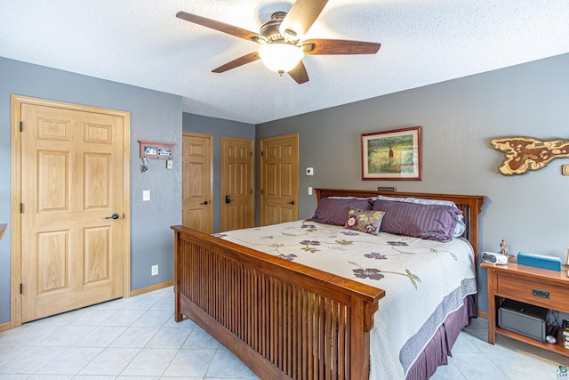 bedroom featuring a ceiling fan, light tile patterned flooring, a textured ceiling, and baseboards