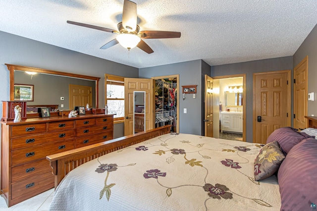 bedroom featuring a closet, a spacious closet, ceiling fan, a textured ceiling, and ensuite bath