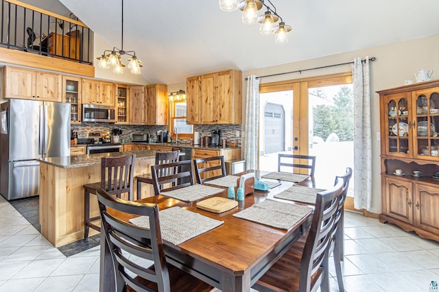 dining space with lofted ceiling, french doors, light tile patterned flooring, and a notable chandelier