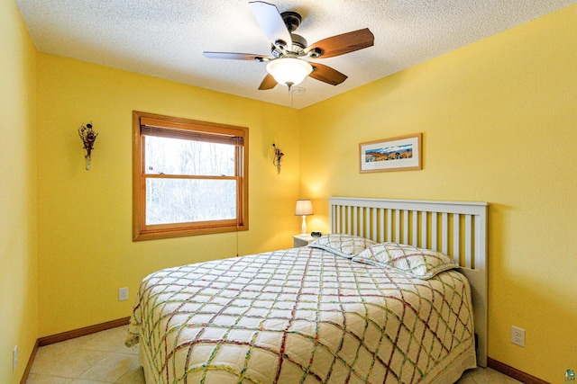 bedroom with a textured ceiling, tile patterned flooring, a ceiling fan, and baseboards