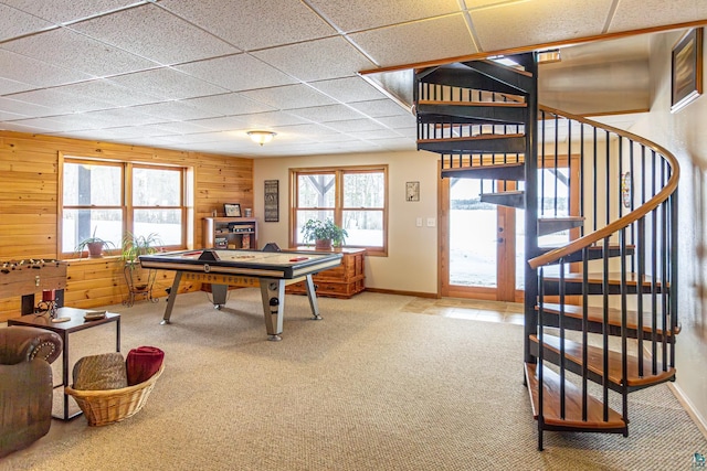 rec room featuring carpet floors, a drop ceiling, wooden walls, and baseboards