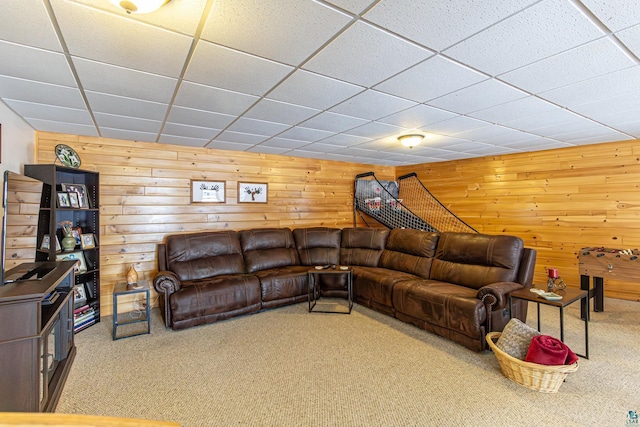 carpeted living room featuring a paneled ceiling and wood walls