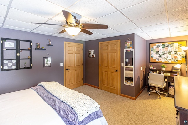 carpeted bedroom with ceiling fan, a drop ceiling, and baseboards