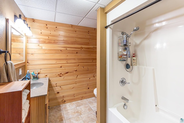 full bathroom with a drop ceiling, tile patterned flooring, toilet, wooden walls, and vanity