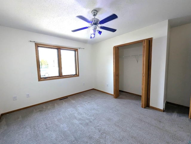 unfurnished bedroom with baseboards, a ceiling fan, light colored carpet, a textured ceiling, and a closet