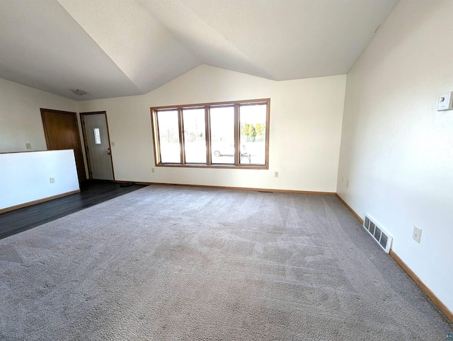 carpeted spare room with baseboards, visible vents, and vaulted ceiling