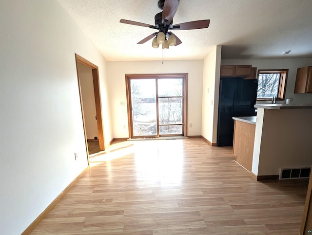 interior space featuring light wood-style floors, freestanding refrigerator, visible vents, and a textured ceiling